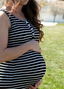 Pregnant woman standing on a sidewalk considering adoption